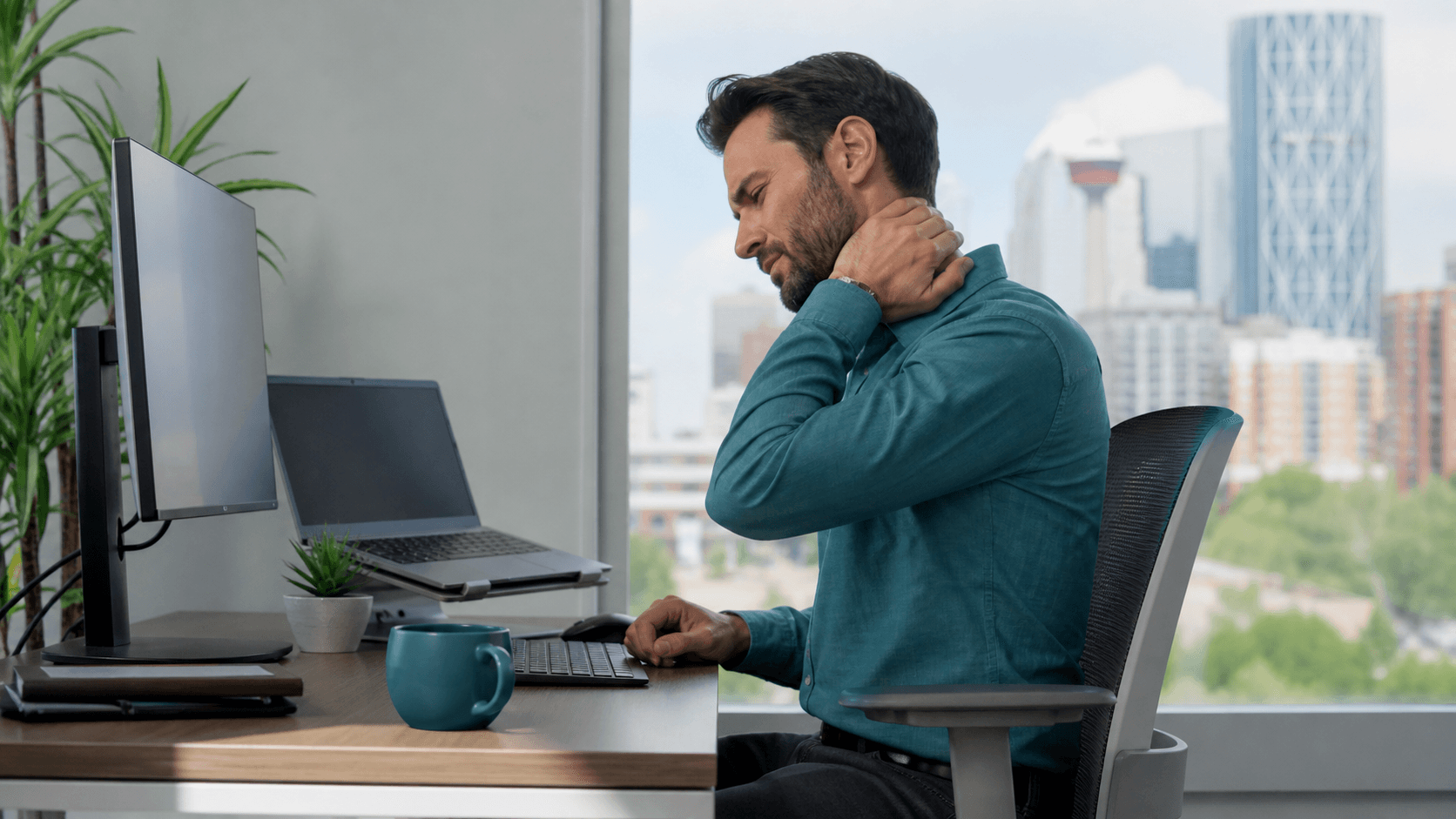 Calgary office worker experiencing neck pain at a computer workstation with an eye-level monitor.